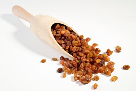 Raisins in a wooden spoon on a white background, isolatedの写真素材