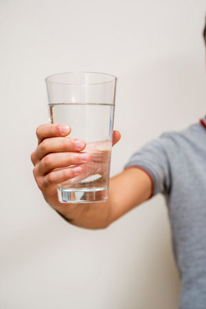 Man holding a glass of water on white background. Focus on glass.の写真素材