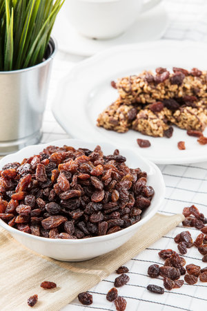 Raisins in a bowl on a white wooden background. Selective focus.の写真素材