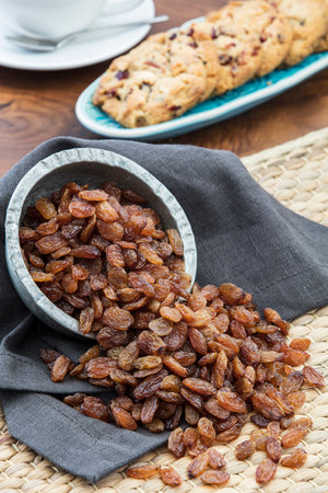 Raisins in a bowl and oatmeal cookies on a wooden tableの写真素材
