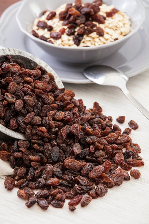 Raisins and oatmeal in a bowl on a wooden tableの写真素材
