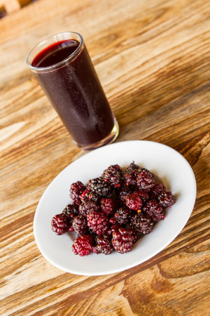 Bowl with blackberries and a glass of juice on wooden tableの写真素材