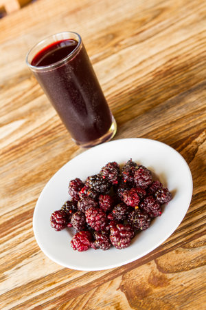 Ripe blackberries and a glass of juice on a wooden tableの写真素材