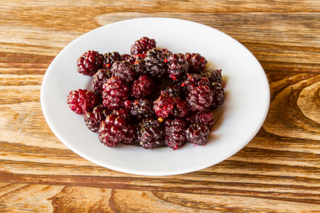 Plate with frozen blackberries on wooden table. top viewの写真素材