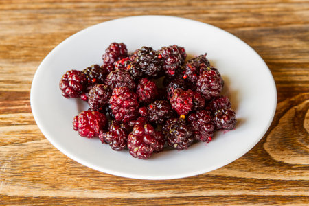 Frozen mulberry in a white plate on a wooden table.の写真素材
