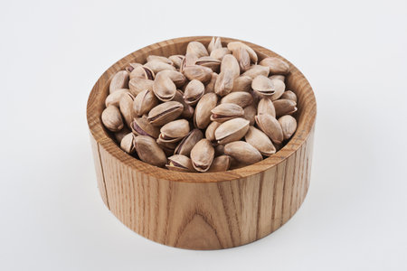 Pistachio nuts in wooden bowl isolated on white background.の写真素材
