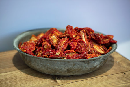 Dried tomatoes in a bowl on a wooden table. Selective focus.の写真素材
