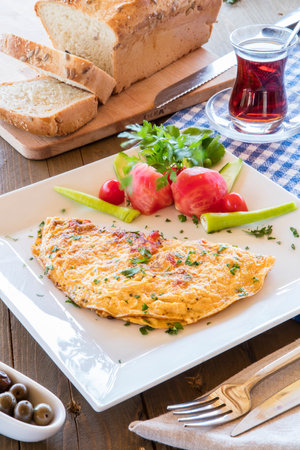 Omelet with tomato, cucumber and parsley on white plateの写真素材
