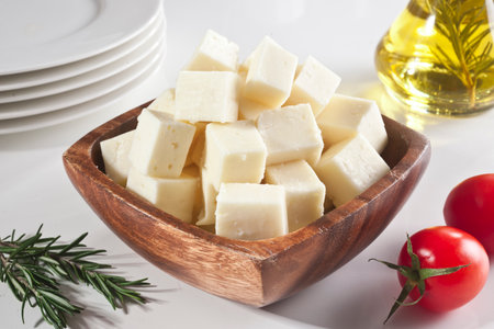 Feta cheese in a wooden bowl with olive oil, tomatoes and rosemaryの写真素材