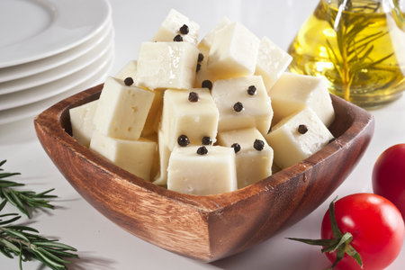 Feta cheese with black pepper in a wooden bowl on a white backgroundの写真素材