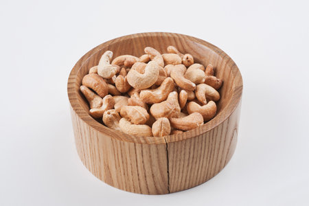 Cashew nuts in wooden bowl isolated on white background with clipping pathの写真素材