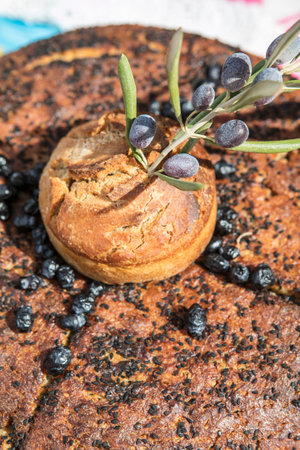 Freshly baked bread with olives and olive branch on wooden table