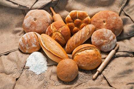 assortment of baked bread and rolls with flour on sackcloth background