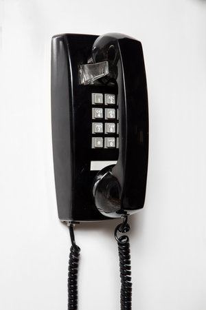 Black telephone on the white wall. Close-up. selective focusの写真素材