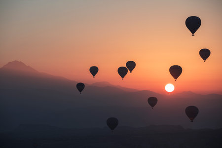 Hot air balloons flying over the mountains at sunset, Cappadocia, Turkeyの写真素材