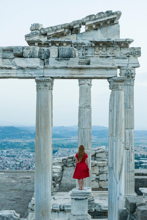 A young woman in a red dress stands on the ruins of the ancient city of Ephesus, Turkeyの写真素材