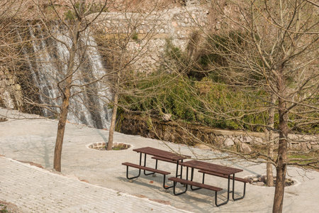 Wooden table and benches on the background of a waterfall in the park