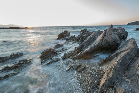 Beautiful seascape with rocks and sea waves at sunset.