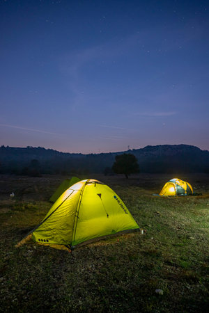 camping in the mountains at night with starry sky and starsの写真素材