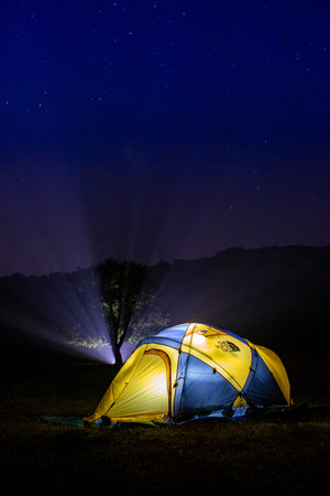 Camping in the mountains at night with a beautiful starry skyの写真素材