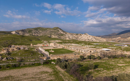 Aerial drone view of Tripolis Ancient City near Buldan in Denizli, Turkey, showing ancient Roman ruins, stone structures, columns, and scenic hillside landscape from above.の写真素材