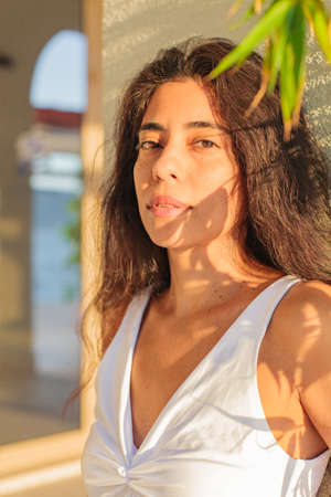 romantic woman looking in camera, smilling with shadow of leaves on face. Sunny day.の写真素材