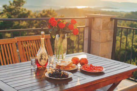 Table with food and drinks in sunset, with red flowers. Romantic dinnerの写真素材