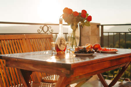Table with food and drinks in sunset, with red flowers. Romantic dinnerの写真素材