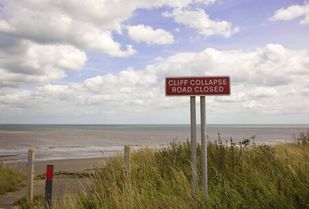 a cliff collapse sign in summer under a blue skyの写真素材