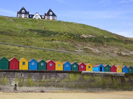 colourful beach huts at the coast with a house on a hillの写真素材