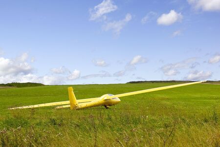 a yellow glider on an airfield in summerの写真素材
