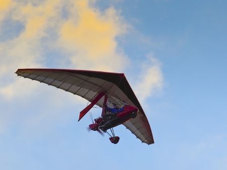 a microlite flying near clouds in summerの写真素材