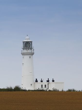 a coastal lighthouse in front of a plowed fieldの写真素材