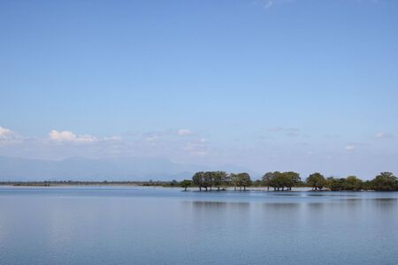 a beautiful lake with a blue sky and mountains in the background at udawalawe national park sri lankaの写真素材