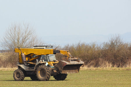 a yellow farm loader in a field in springtime