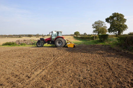 sunny autumn landscape with a three wheeled tractor cultivating a field