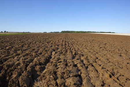 a newly plowed field in late summer at harvest time in the yorkshire wolds england under a clear blue skyの写真素材