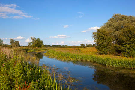 a scenic canal waterway with reflections in summer under a blue cloudy sky in yorkshireの写真素材