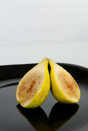 one fig cut in half, on a black plateの写真素材