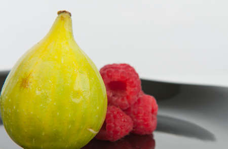 green fig and rasberry in plateの写真素材