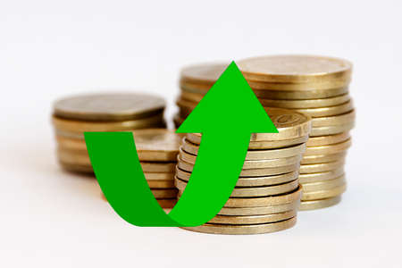 Stacks of coins with a green arrow up on themの写真素材