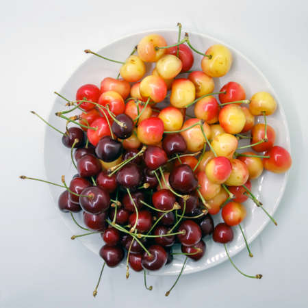 Red and yellow cherry in a white bowlの写真素材
