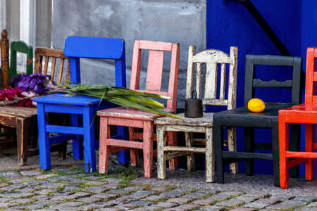 Old multi-colored kids high chairs stand in a row with various objects on themの写真素材