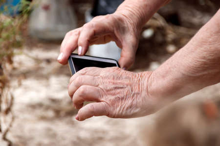 The hands of an elderly woman with a mobile phoneの写真素材