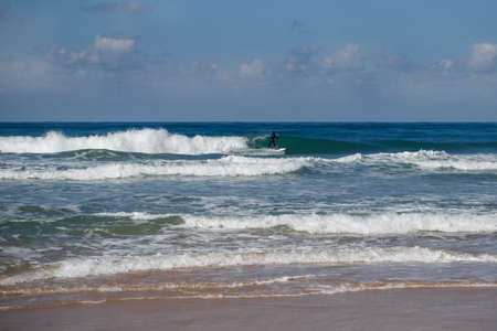 The surfer slips on the wave in the sea foam of the coastal waters of the Mediterranean Seaの写真素材