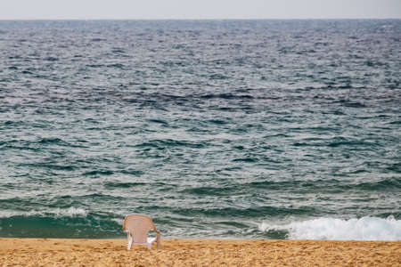Beach white plastic chair stands on the sandの写真素材
