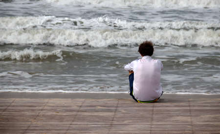 The back of a man sits on a wooden platformの写真素材