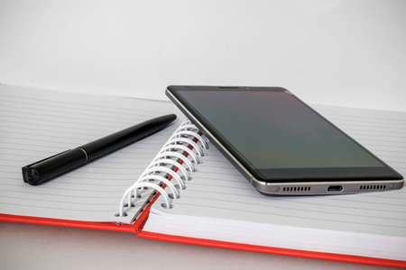 Open notebook with pen and mobile phone on itの写真素材