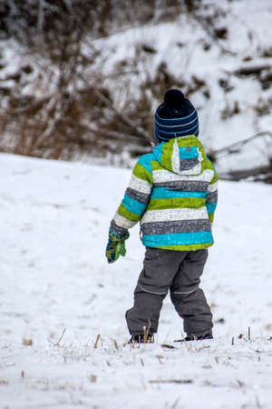 Warmly dressed boy standing in the snowの写真素材