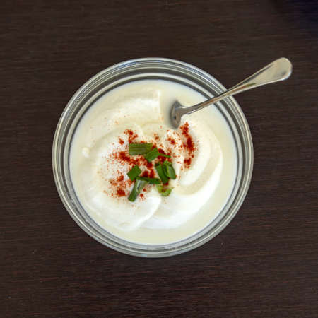 Sour cream in a cup decorated with paprika and green onion sliced. Top viewの写真素材